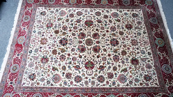 A Tabriz Shah Abass carpet, Persian, the ivory field with an allover design of palmettes and trailing floral sprays; a madder border with roundels of