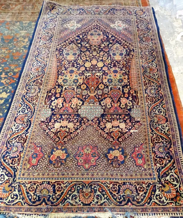 A Kashan prayer rug, Persian, the indigo mehrals with a border at the base rising to three abundantly filled vases of flowers; above are three flower