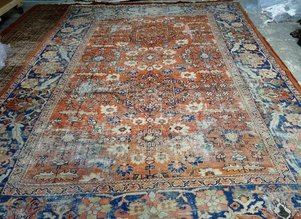 A Mahal carpet, Persian, the madder field with a central flower medallion and two supporting medallions, angular floral sprays; a wide indigo border w