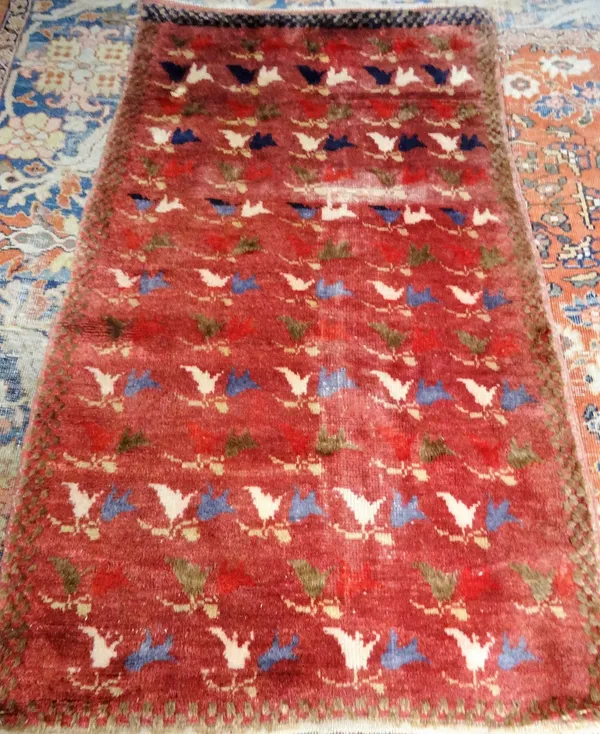 A Khoran rug, the burgundy field rows of pairs of lily flowerheads, a brown chequered border, 180cm x 105cm.