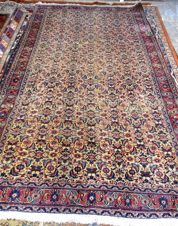 A Mashhad carpet, Persian, the pale fawn field with an allover herate design; a burgundy rosette, boteh and floral vine border, 268cm x 160cm.