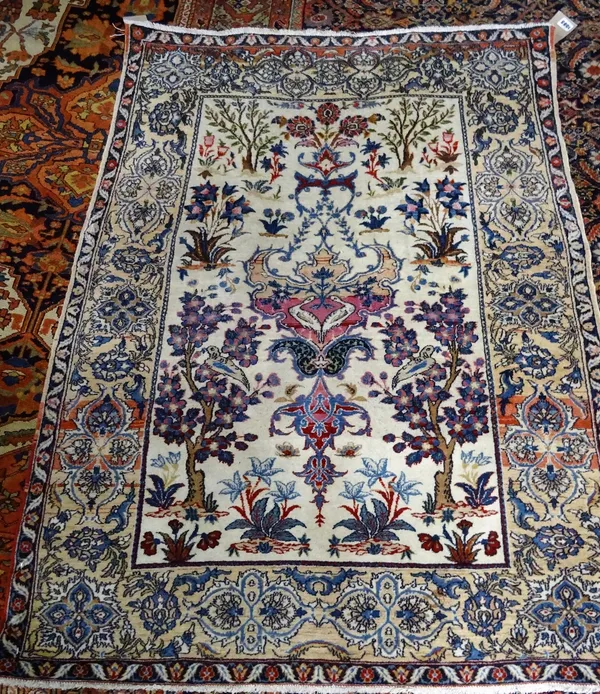 A fine Esfahan rug, Persian, the ivory field with a winged medallion, two flowering trees, rising to flowering plants above, a pale madder border with