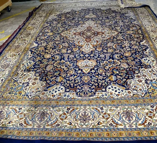 An Indian carpet, the indigo field filled with floral sprays, a central ivory border, matching spandrels; an ivory palmette and scrolling leaf and vin