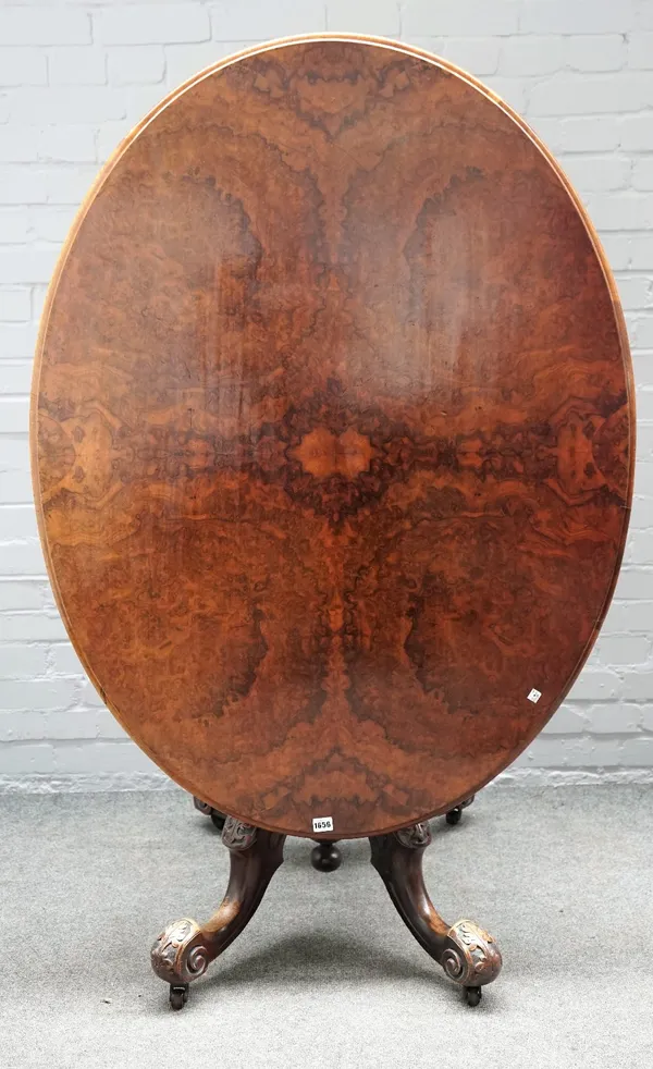 A Victorian figured walnut, oval snap top centre table, on four carved downswept supports, 130cm wide x 71cm high.