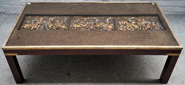 A brass bound rectangular coffee table, inset with relief of a medieval battle scene, 132cm wide x 42cm high.