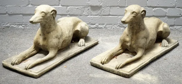 A pair of reconstituted stone figures of recumbent greyhounds on rectangular bases, 70cm wide x 40cm high.