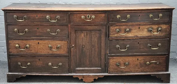 A George III oak low dresser, the rectangular top above three frieze drawers with six drawers below, flanking a central cupboard, on bracket feet, 170