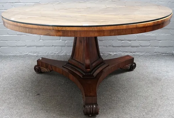 A late Regency rosewood breakfast table, the circular tilt-top on a mahogany sunk panelled spreading triangular pillar with beaded borders, gadrooned