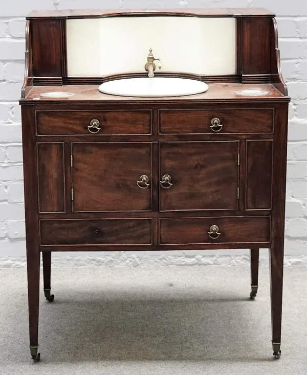 A late George III mahogany washstand, with integral ceramic reservoir and bowl on tapering square supports, 77cm wide x 103cm high.