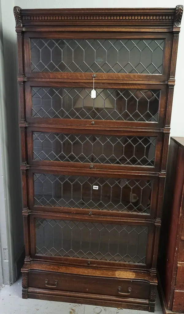 A carved oak Globe Wernicke five tier bookcase, with fluted pilasters, leaded glazed up and over doors, with a projecting drawer below, 90cm wide x 37