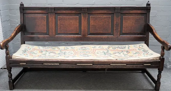 A George III oak open arm settle with four panel back on turned supports, 180cm wide x 102cm high.