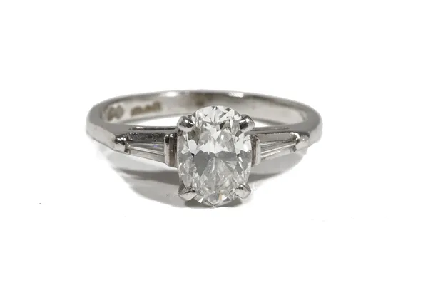 A platinum and diamond single-stone ring, the oval-cut diamond measuring 1.05ct approximately, claw-set with tapered baguette-cut diamonds to the shou