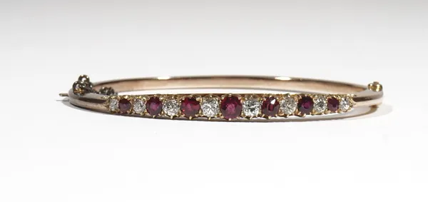 A ruby and diamond-set hinged bangle, claw-set with alternating cushion shaped rubies and diamonds, approximate total diamond weight 0.95ct, the yello