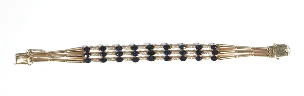 A sapphire and diamond-set triple row bracelet, set with alternating oval-cut claw-set sapphires, between diamond-set three stone gold  links, with gr