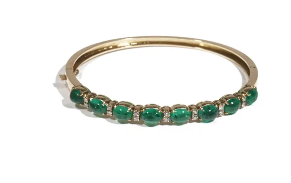 A cabochon emerald and diamond-set gold oval hinged bangle, set with a row of eight oval cabochon emeralds, alternating between two circular-cut diamo