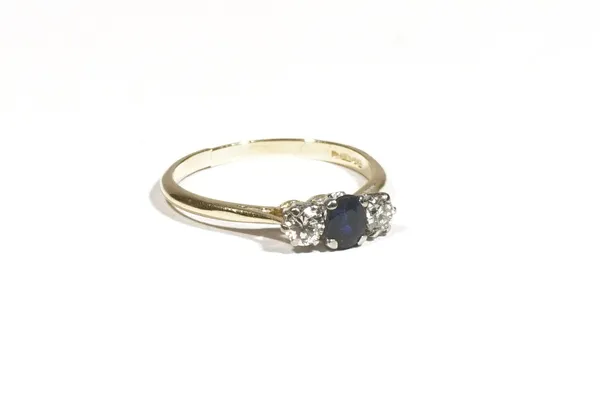 An 18ct gold three stone sapphire and diamond ring, the oval-cut sapphire between two circular-cut diamonds, ring size J, 1.9g gross.