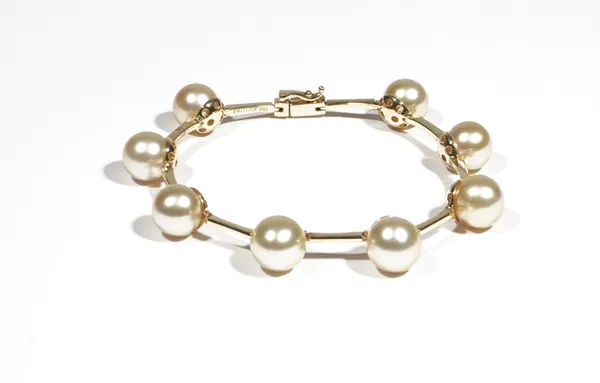 A gold and cultured pearl-set bracelet by Autore, set with eight cultured pearls, between baton links, to an elongated box and tongue clasp, with safe