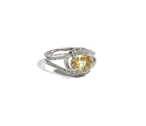 An 18ct white gold, yellow sapphire and diamond-set dress ring, the oval-cut yellow sapphire approximately 1.95ct, claw-set to an openwork cross-over