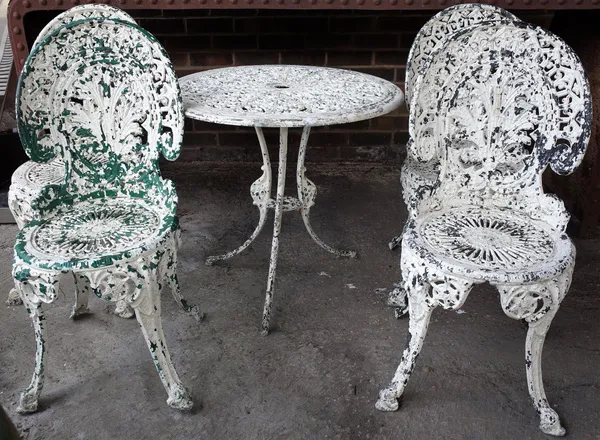 A white painted cast aluminium garden table, 69cm diameter x 82cm high, and a matching set of four chairs, 37cm wide x 85cm high (5).