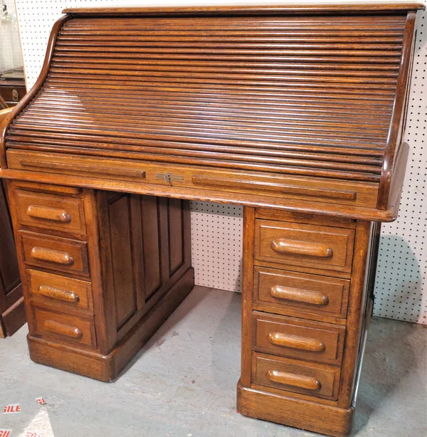 An early 20th century oak roll top pedestal desk, fitted interior, nine drawers about the knee, 125cm wide x 125cm high.