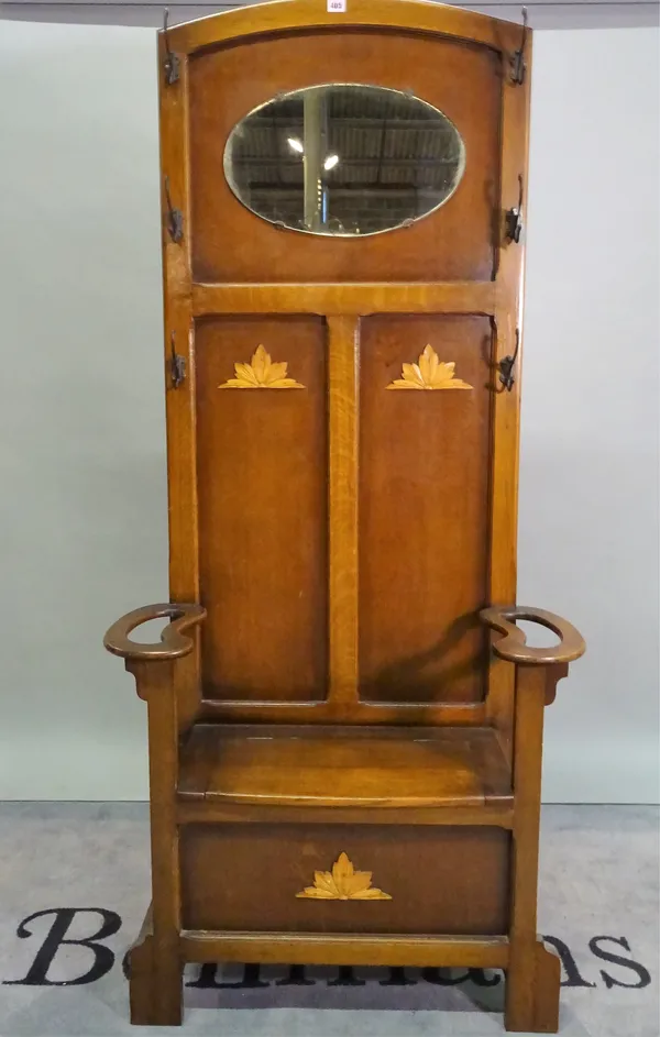 An early 20th century arts and crafts oak hall stand with an oval mirrored back lift top seat, 85cm wide x 120cm high.