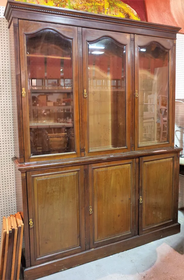 A late Edwardian mahogany bookcase cabinet with arch bevelled glass doors on a plinth base, 183cm wide x 233cm high.