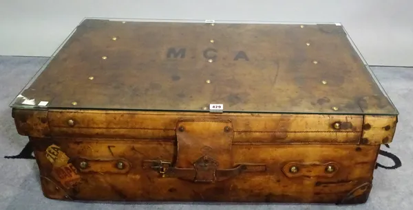 A coffee table with rectangular loose glass top on a brass studded polished leather suitcase, 91cm wide x 32cm high.