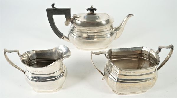 Silver tea wares, comprising; a teapot having black fittings, Birmingham 1922, a twin handled sugar bowl and a milk jug, both Birmingham 1925, all in