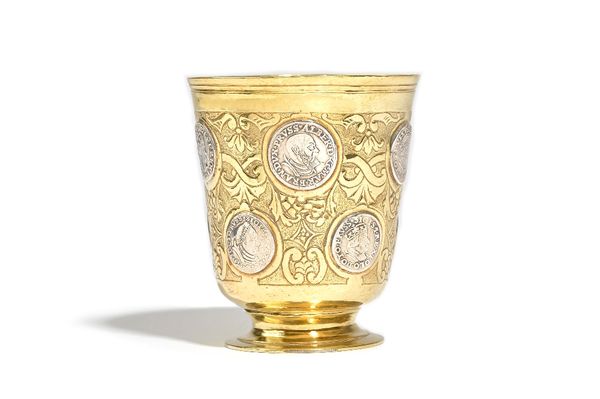 A European parcel gilt beaker, the tapered body with scroll decoration, mounted with a variety of mostly Polish silver coins, indistinct mark to base,