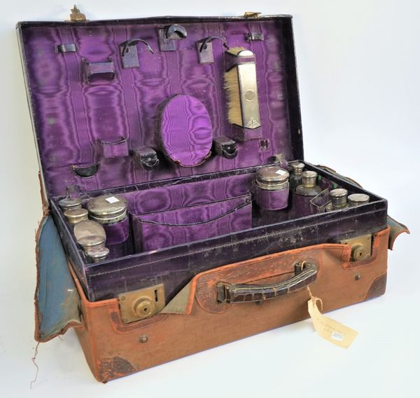 A silver mounted travelling part toilet set, fitted with a variety of bottles, jars, brushes and further accessories, (several pieces lacking).