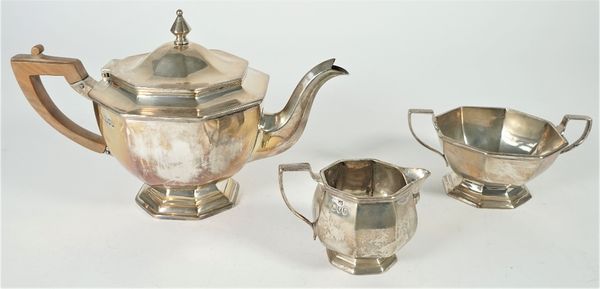 Silver tea wares, comprising; a teapot with a wooden handle, a twin handled sugar bowl, both London 1900 and a milk jug, of similar octagonal form, Lo