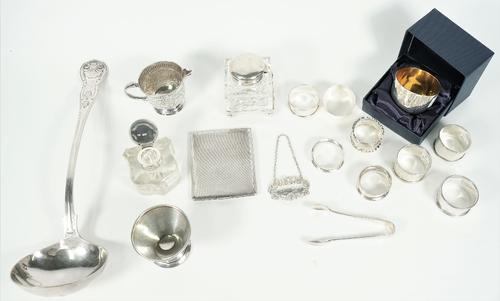 Silver, comprising; a rectangular cigarette case, a tea strainer stand, a decanter label detailed Sherry, eight napkin rings, a tumbler cup with a box