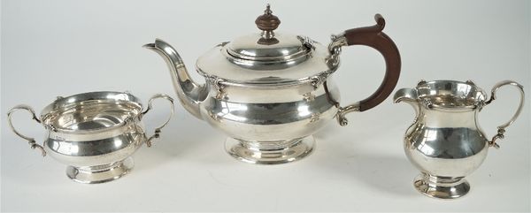 A silver three piece tea set, comprising; a teapot with brown fittings, a twin handled sugar bowl and a milk jug, each piece of compressed baluster fo