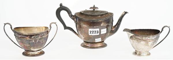 Silver tea wares, comprising; a teapot with black fittings, Sheffield 1910, a twin handled sugar bowl, Sheffield 1911 and a milk jug, Sheffield 1910,