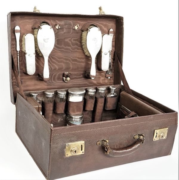 A lady's silver mounted travelling dressing/toilet set, the fittings including; a hand mirror, two hairbrushes, two clothes brushes and eight faceted