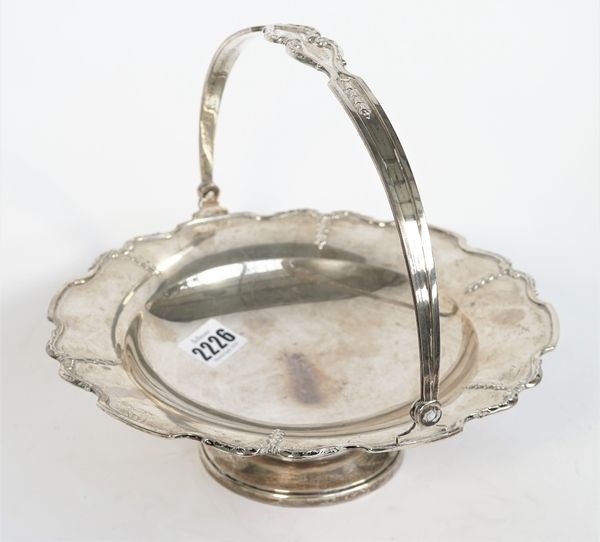 A silver cake or fruit basket, of shaped circular form, having a decorated rim, with a swingover handle, raised on a circular foot, diameter 22.5cm, B