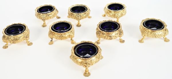 A group of eight gilt metal salts, mid-19th century, each of shaped circular form, with floral and scrolling decoration, raised on three feet, having