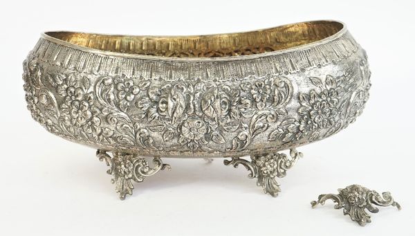 A large boat shaped centrepiece bowl, having floral, foliate and scroll embossed decoration, raised on cast and pierced feet, (one foot detached, but