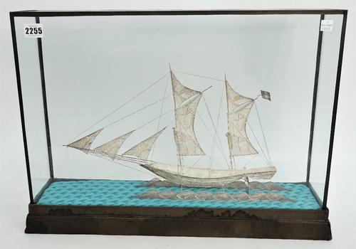A filigree model of a two masted sailing ship, displayed in a glazed wooden case, length of case base 55cm.