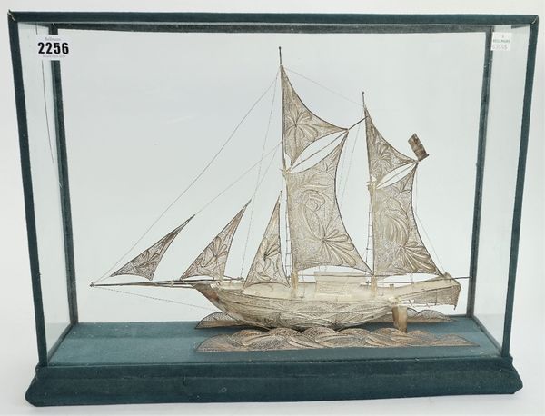 A filigree model of a two masted sailing ship, displayed in a glazed wooden case, length of case base 50cm.