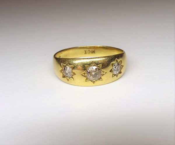 A gold and diamond set three stone ring, star gypsy set with a row of cushion shaped diamonds, detailed 18 CT, ring size P and a half, gross weight 4.