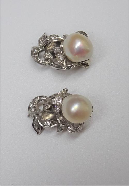 A pair of diamond and cultured pearl set earclips, each designed as a foliate scrolling spray, mounted with a single cultured pearl at the top and oth