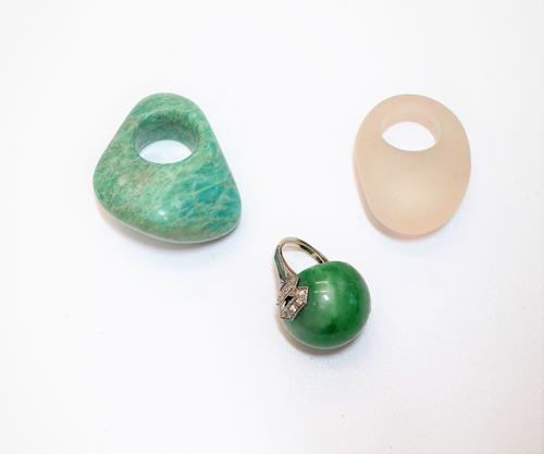 A green hardstone and diamond ring, mounted with a circular green hardstone to the centre, between diamond set shoulders, in a geometric design and tw