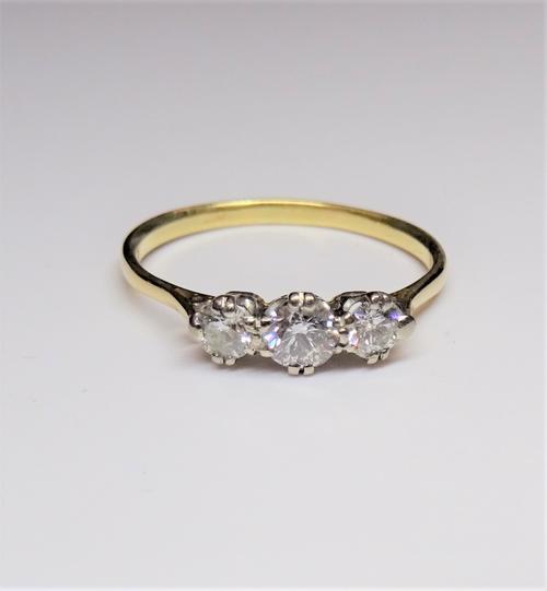 A gold and diamond set three stone ring, claw set with a row of circular cut diamonds and with the principal diamond mounted at the centre, ring size