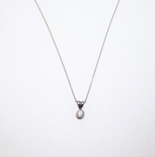 A platinum and diamond single stone pendant, collet set with a circular cut diamond, with a 9ct white gold oval link neckchain, on a boltring clasp.