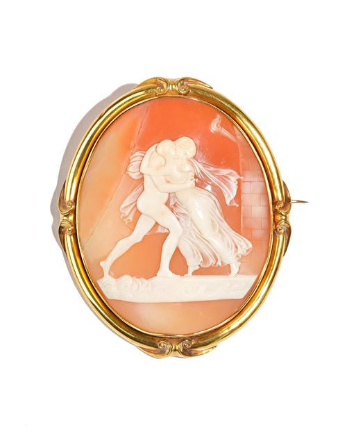 A Victorian gold mounted oval shell cameo brooch, carved as two classical figures, the setting with scroll motifs at intervals, with a case. Illustrat