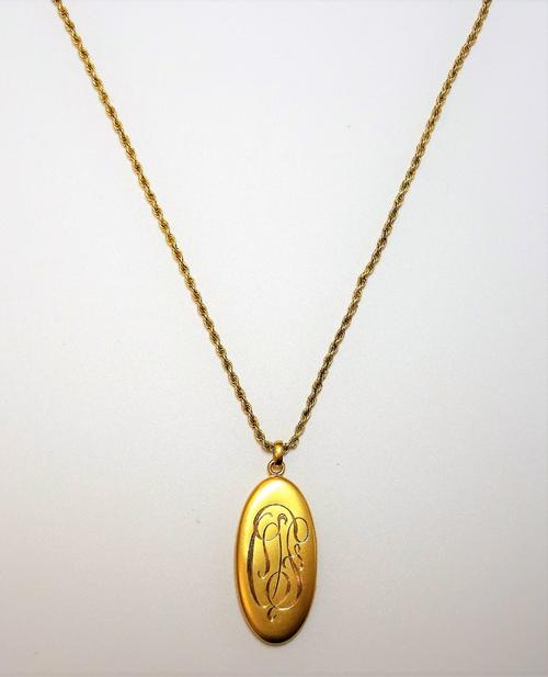 A gold ropetwist link long guard chain, detailed 9 CT, with a boltring clasp, detailed 9 CT and a gold oval pendant locket, monogram engraved, detaile