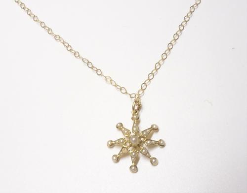A gold and seed pearl set pendant, designed as an eight pointed starburst, (one seed pearl lacking), circa 1900, with a later 9ct gold neckchain, on a
