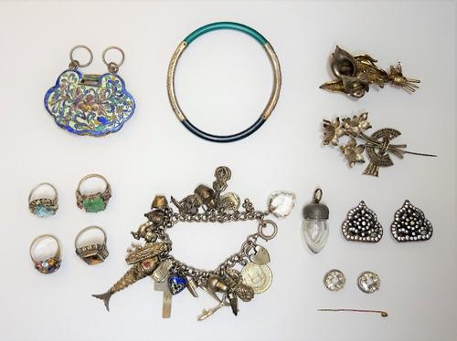 A group of jewellery, comprising; a charm bracelet, fitted with a variety of mostly silver charms, four gem set rings, two brooches, a pair of colourl
