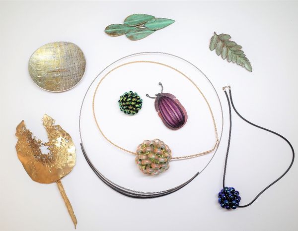 A group of studio jewellery, comprising; a pendant formed as a stylized beetle, two brooches having patinated bronze finishes, two brooches of abstrac